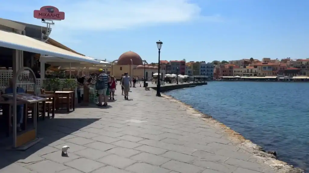 Venetian harbour waterfront with restaurant terraces, the domed Kรผรงรผk Hasan Mosque visible mid-distance and colourful buildings lining the far shore