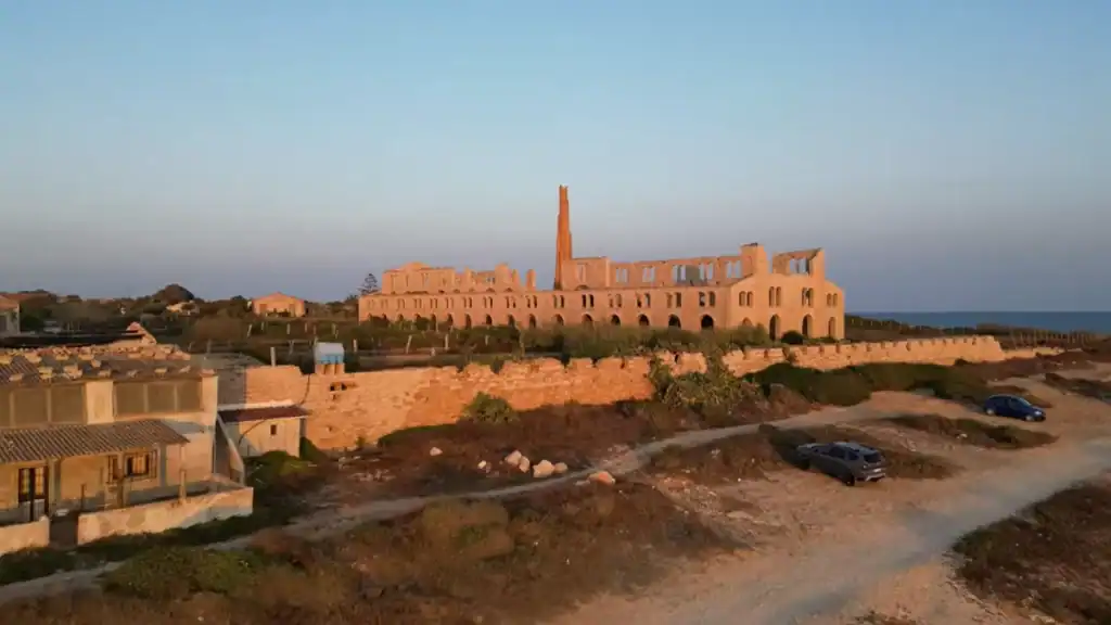 Roofless walls and a solitary brick chimney of Fornace Penna glow amber at dusk, an industrial ruin that rewards Ragusa Ibla travel extended toward the southeastern Sicilian coast