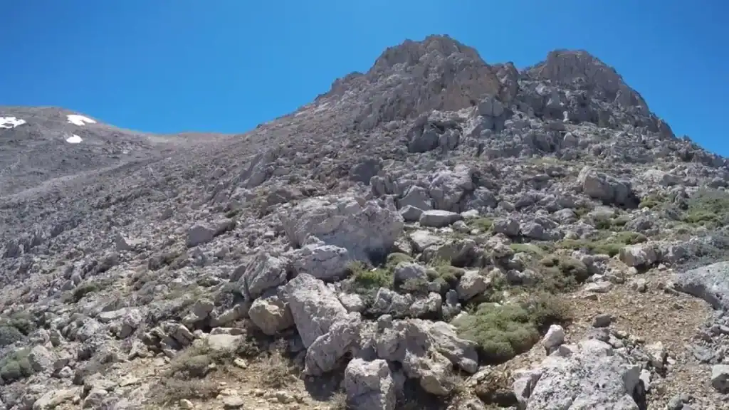 Fractured limestone summit rising above a boulder-strewn slope in the White Mountains of Chania, sparse scrub clinging between the rocks
