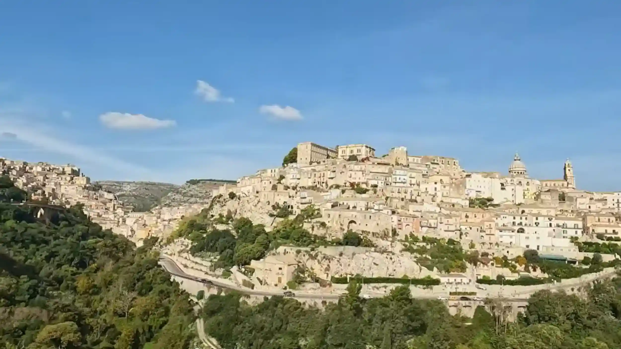 Ragusa Ibla climbs a limestone ridge, its layered Baroque townscape and cathedral dome visible across the valley in this Ragusa guide to the city's most recognisable approach.