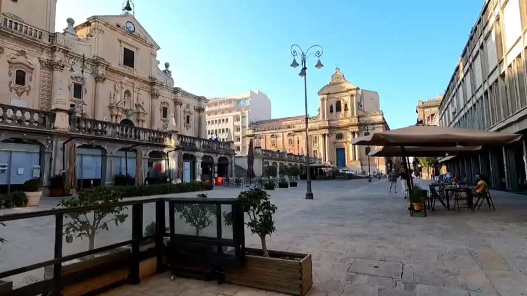 Piazza San Giovanni in Ragusa Superiore, quiet in the morning with café terraces open and the cathedral's baroque facade catching early sun - the kind of place settling into Ragusa tends to begin