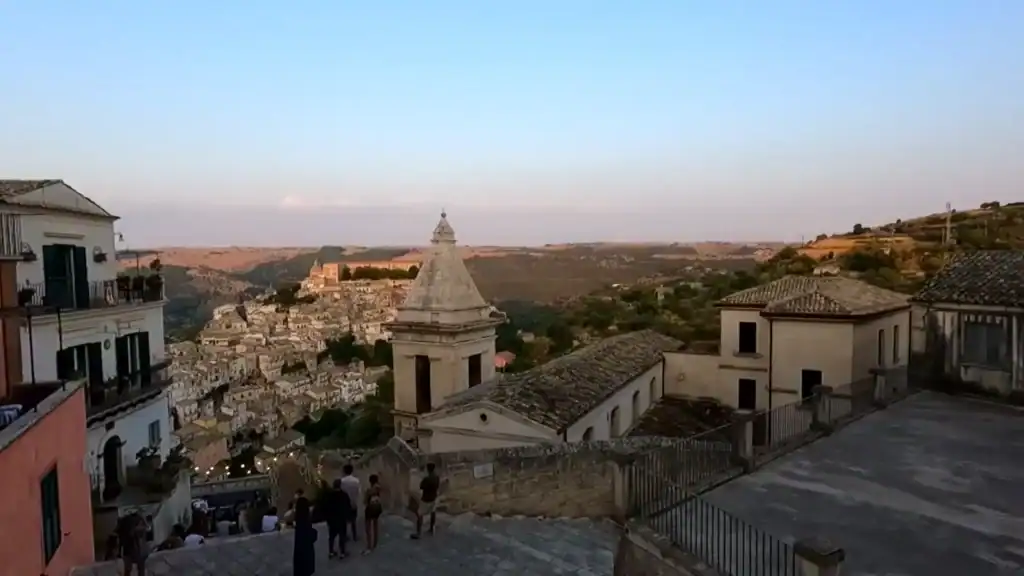 Settling into Ragusa at dusk, with the bell tower of Santa Maria delle Scale in the foreground and Ragusa Ibla's baroque rooftops cascading down into the valley below