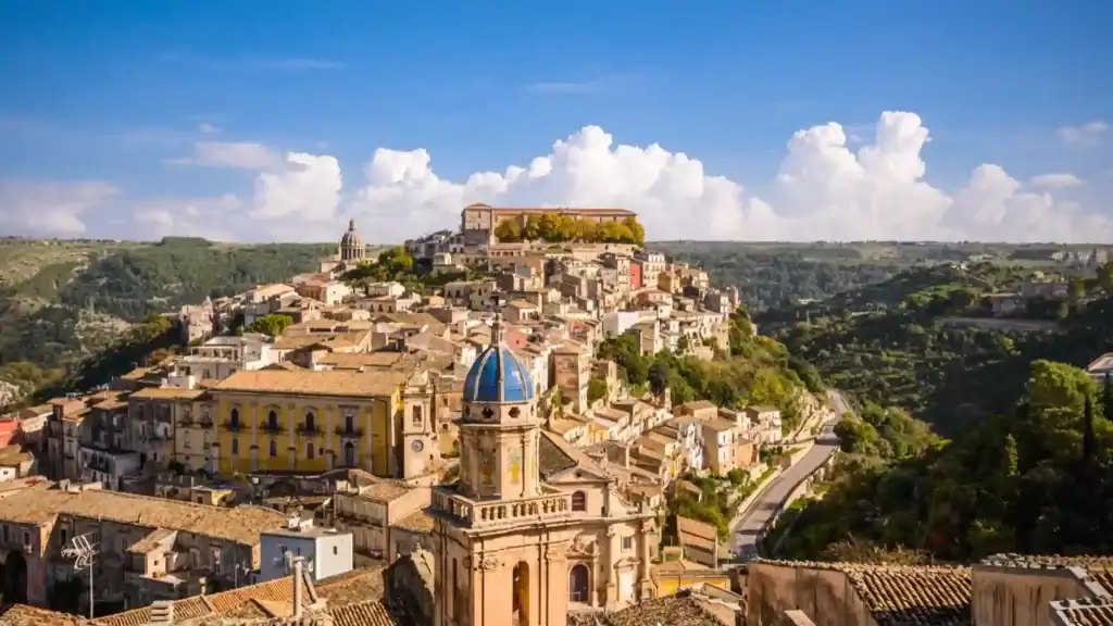 Ragusa Ibla's hilltop baroque townscape with the blue-domed Santa Maria dell'Itria in the foreground and Ragusa Superiore climbing the ridge behind - a Ragusa travel guide essential for anyone exploring southeastern Sicily.