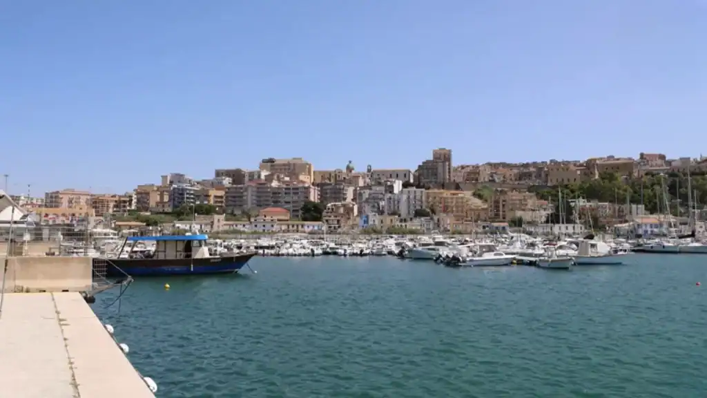 Sciacca's marina packed with moored boats, the old town stacked in layers of ochre and cream buildings rising up the hillside behind it.