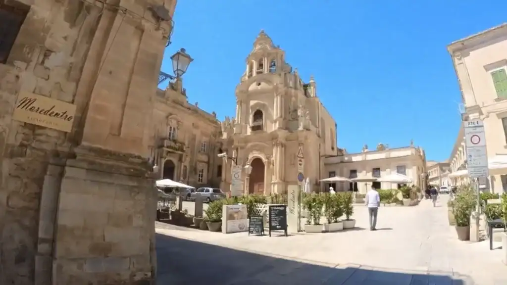 Chiesa di San Giuseppe faces onto an open piazza, its ornate baroque tower above café terraces and a pedestrian crossing the square