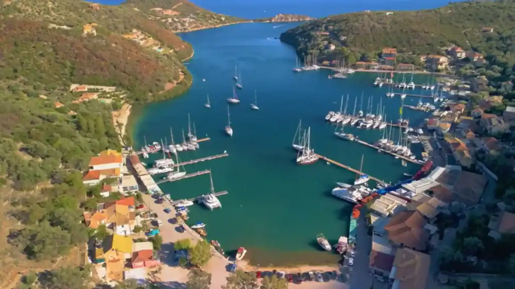 Sivota Lefkada's deep inlet stretching inland between dry scrub-covered hillsides, sailing yachts moored along both pontoons with the bay opening toward the sea in the distance