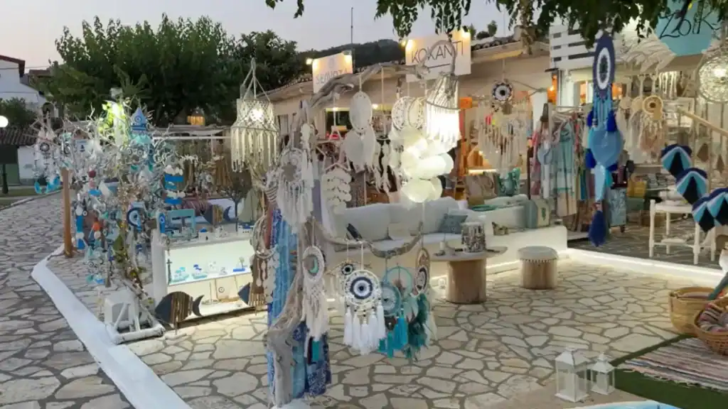 Dream catchers, evil eye charms and driftwood displays outside the Sivota Lefkada boutiques Kokanti and Sea Vota, lit up at dusk on a stone-paved open-air shopping area