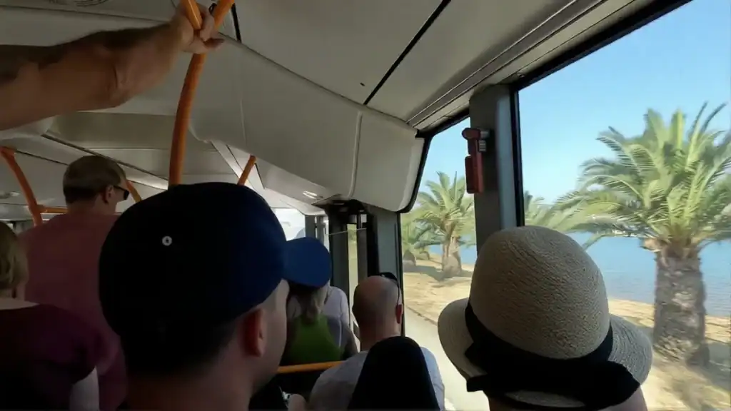 Passengers on a bus heading to Chania, palm trees and the sea visible through the window on one day in Chania