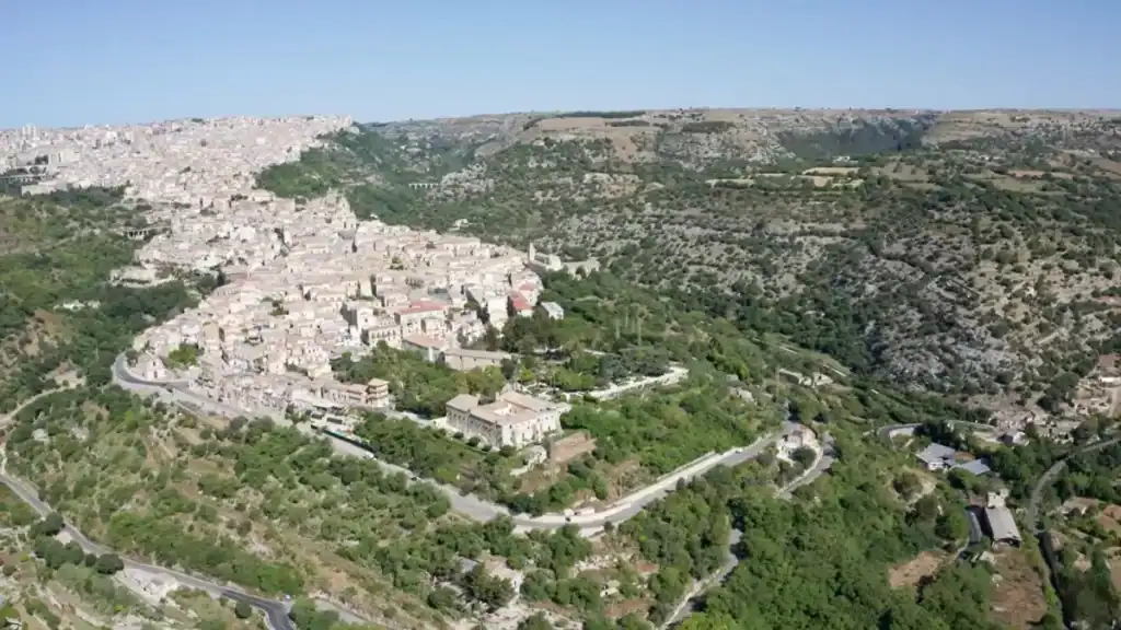 Ragusa Ibla occupying a densely built limestone promontory, encircled by wooded ravines, with the modern upper city spreading across the plateau behind