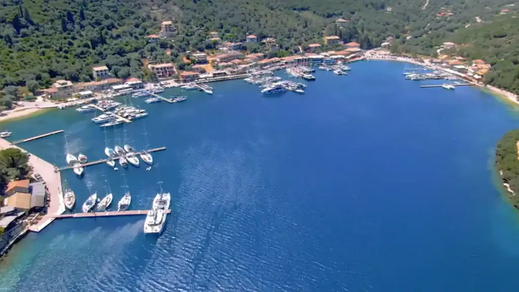 Sailing yachts moored along pontoon jetties in Sivota's sheltered bay, lefkada in may showing the village and wooded hillsides enclosing the deep blue inlet from above