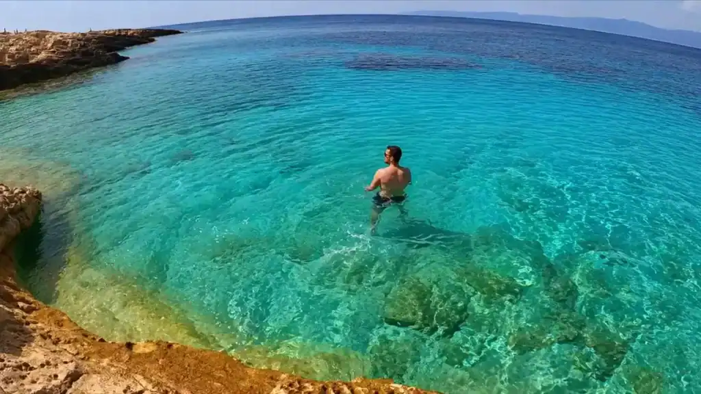 Man wading into turquoise waters at Proizd Island, one of the best Korčula Town day trips