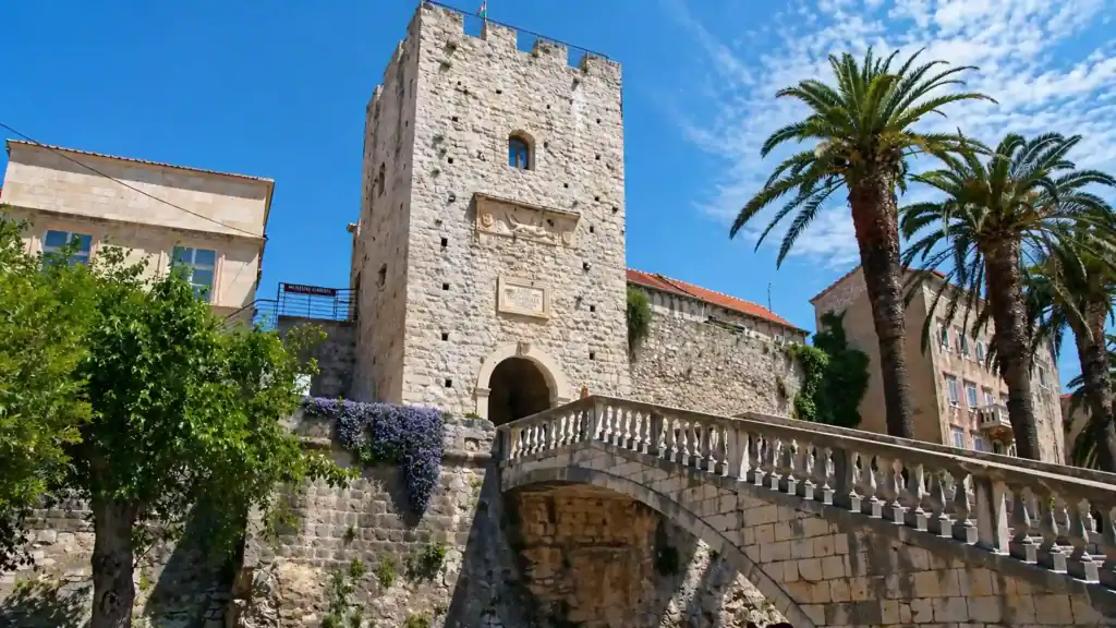 Land Gate and Revelin Tower with man on stone bridge, a day in Korčula Town