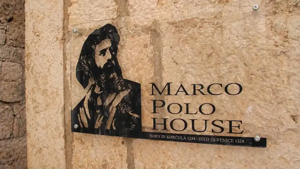 Marco Polo House sign with portrait illustration mounted on a stone wall in Korčula's old town