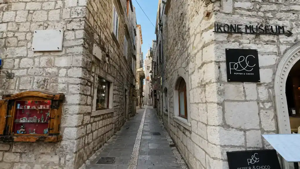 Narrow limestone lane in Korčula town with an Icon Museum sign and small shops tucked into stone walls