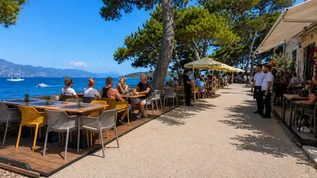 Outdoor cafe terraces lining the waterfront promenade during a day in Korčula Town