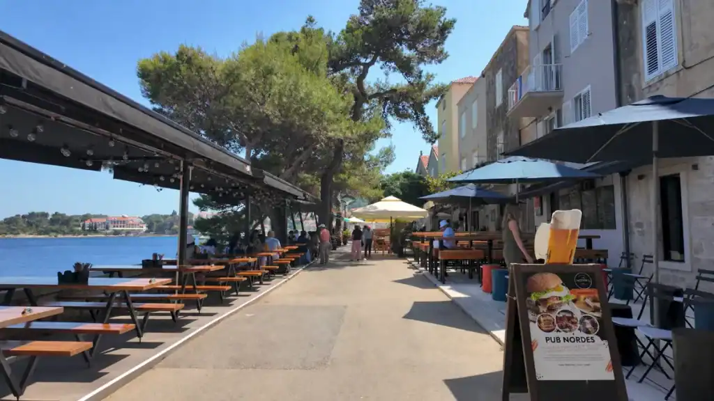 Pub Nordes terrace and waterfront benches along the promenade, a day in Korčula Town