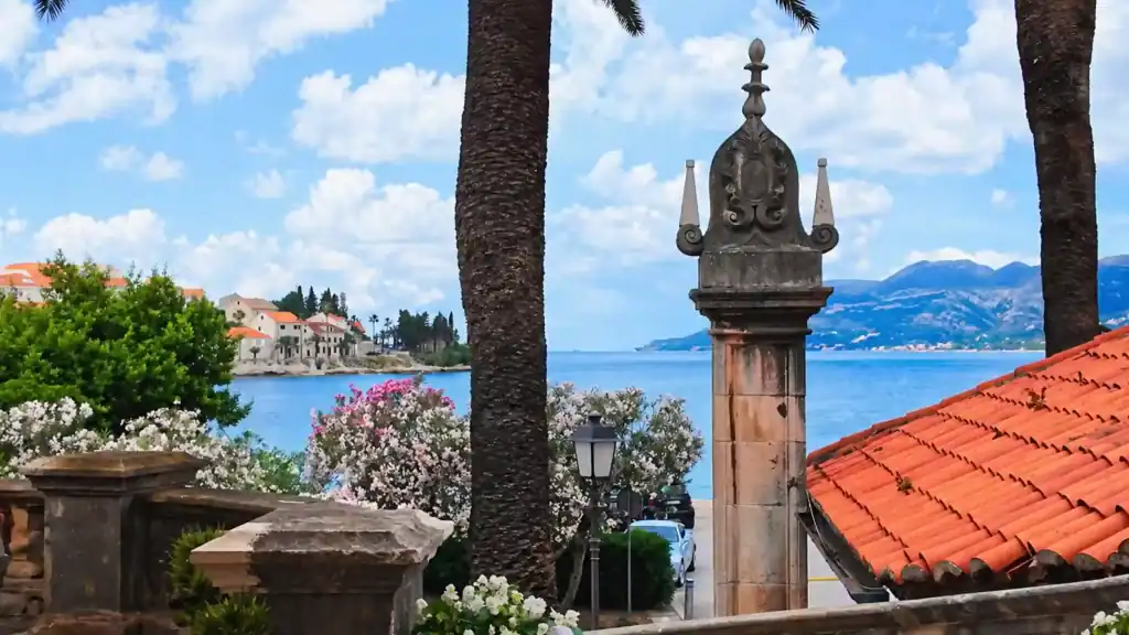 Ornate stone pillar and terracotta rooftops overlooking the Adriatic on a Korčula Town winery day