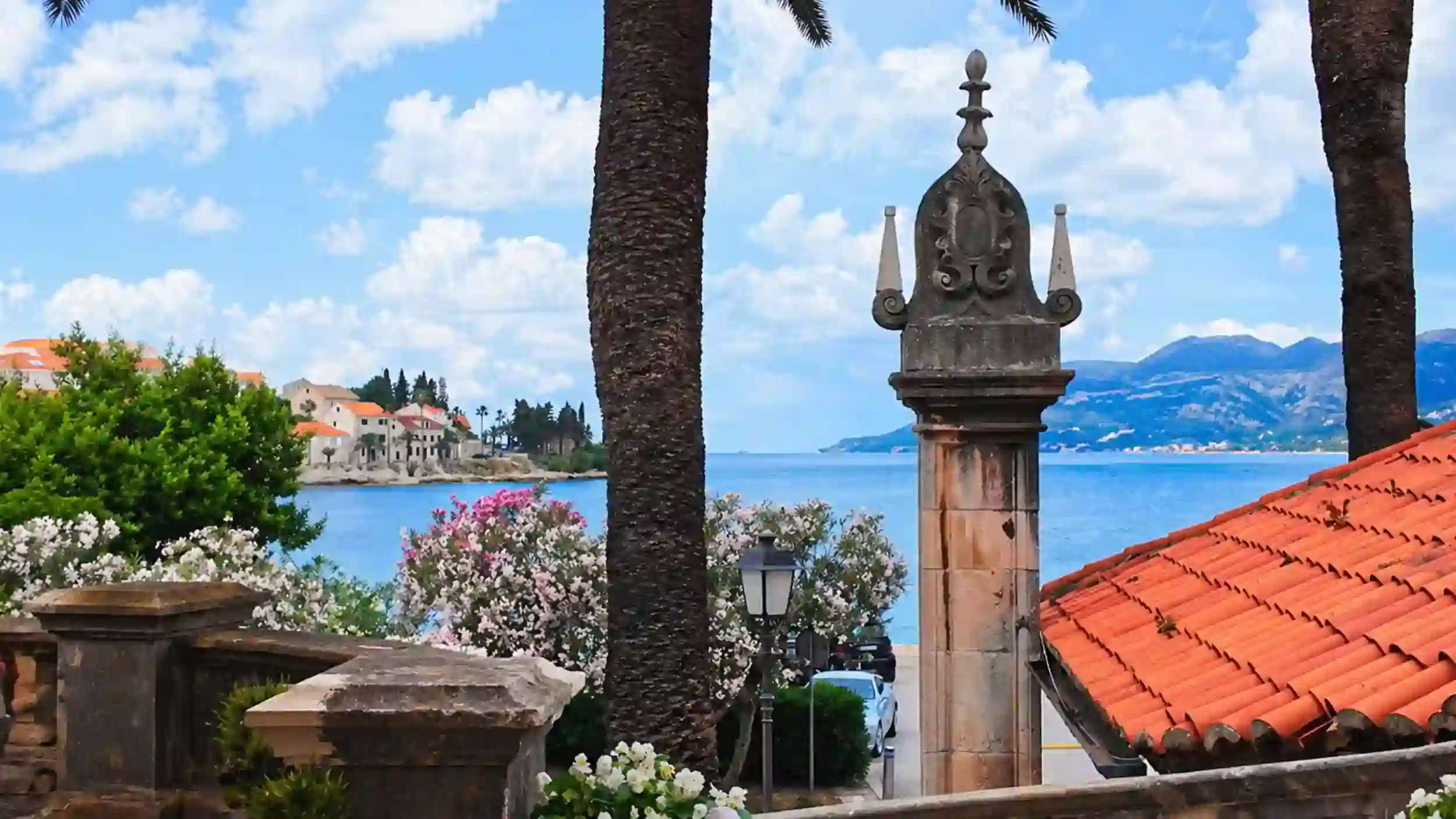 Ornate stone pillar and terracotta rooftops overlooking the Adriatic on a Korčula Town winery day