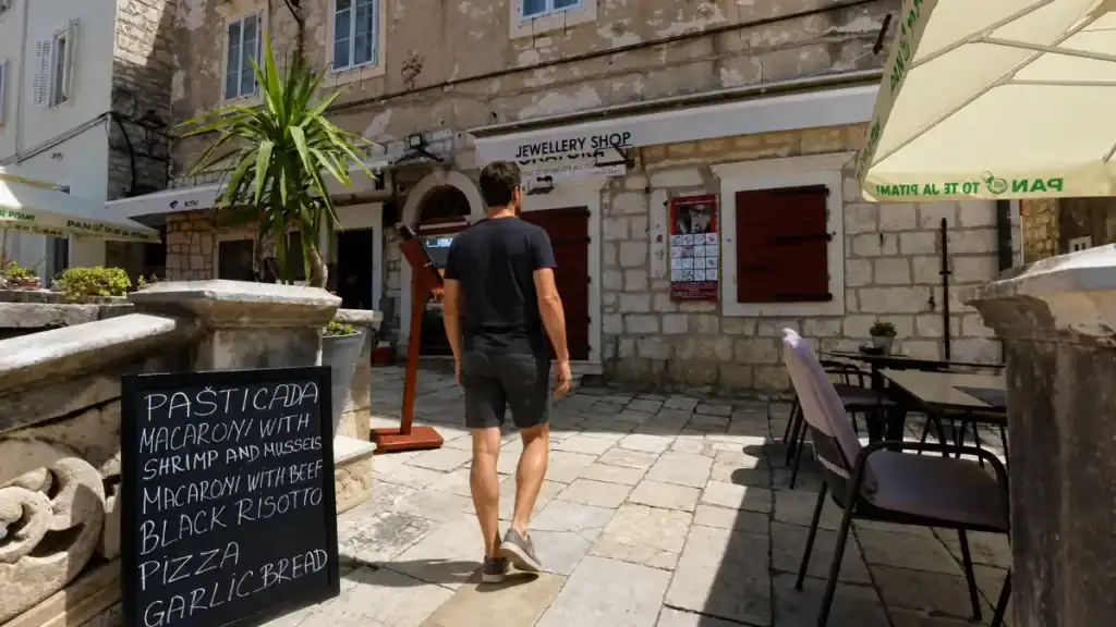 Man walking past a jewellery shop and restaurant menu board in Korčula Old Town