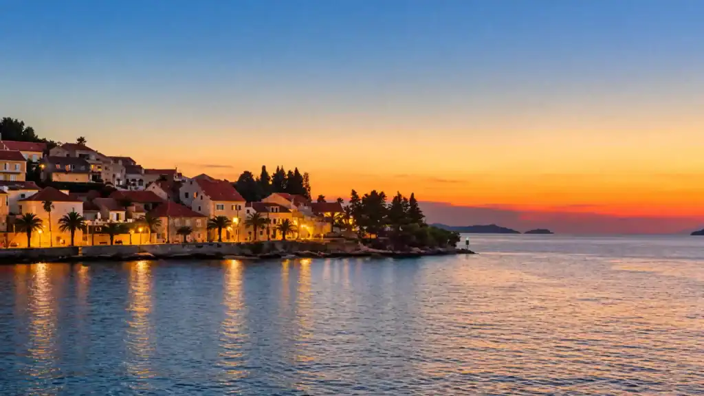 Korčula town sunset over the old town waterfront with glowing harbour lights and orange sky
