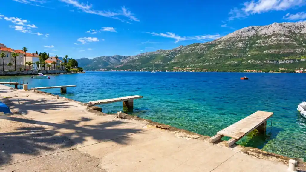 Stone jetties extending into turquoise water along the old town waterfront, typical of the Korčula Town swim spots locals use daily