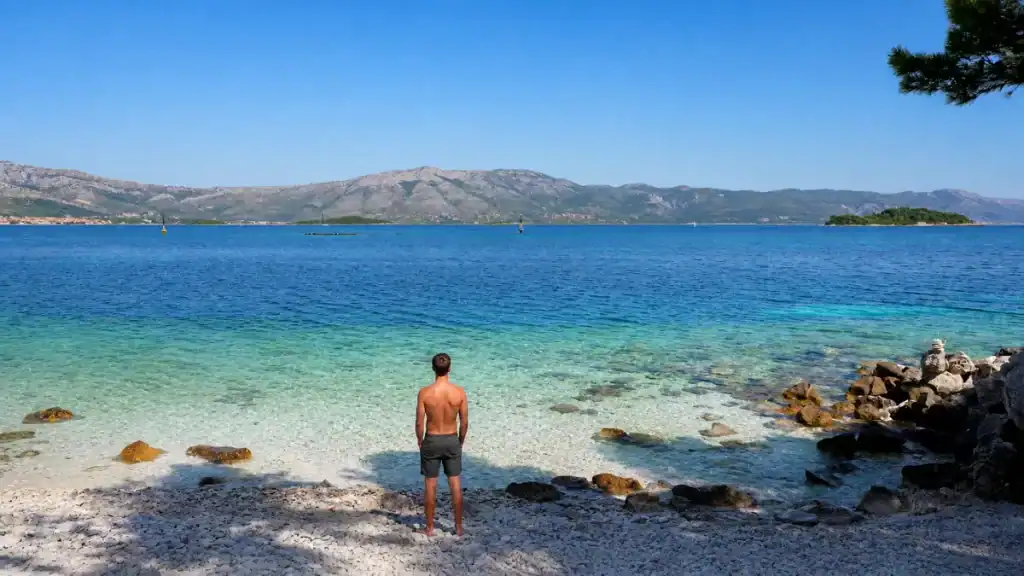 Swimmer pauses on the pebble shore at Vrnik Island beach
