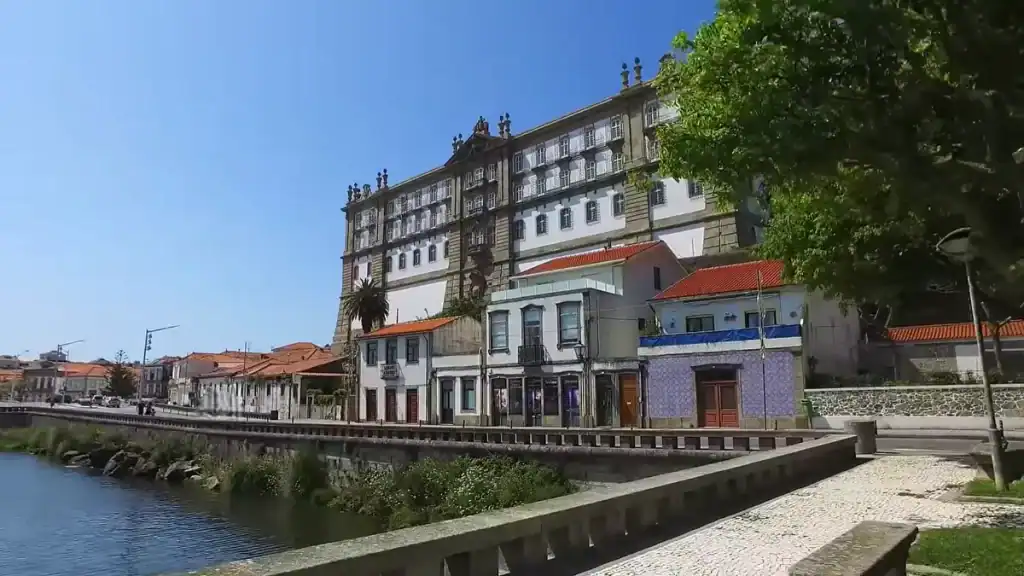 Grand baroque monastery facade rising above tiled shopfronts along a river quay