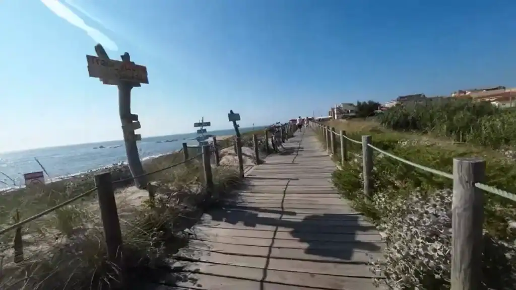Timber boardwalk running along the Atlantic coastline with wooden signposts and parked bicycles