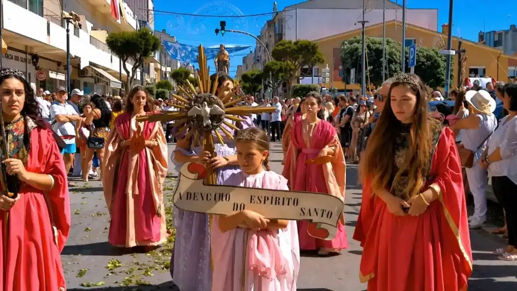 Young girl holding Espírito Santo banner leads robed women through the Vila do Conde festival procession