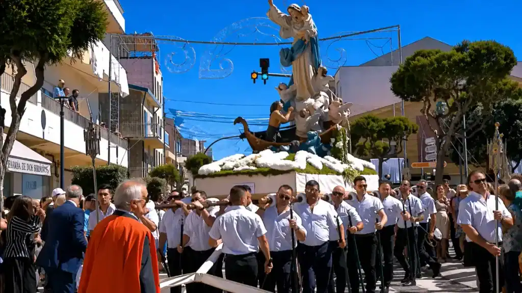 Men carrying a large religious float with Our Lady statue through a crowded town street