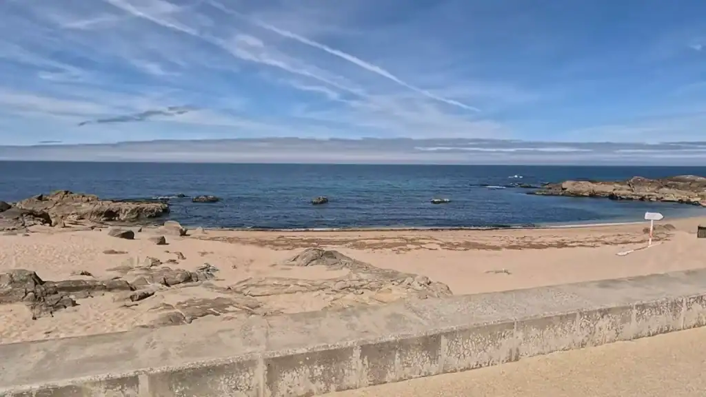 Small sandy cove framed by granite rocks and a low stone seawall facing the Atlantic