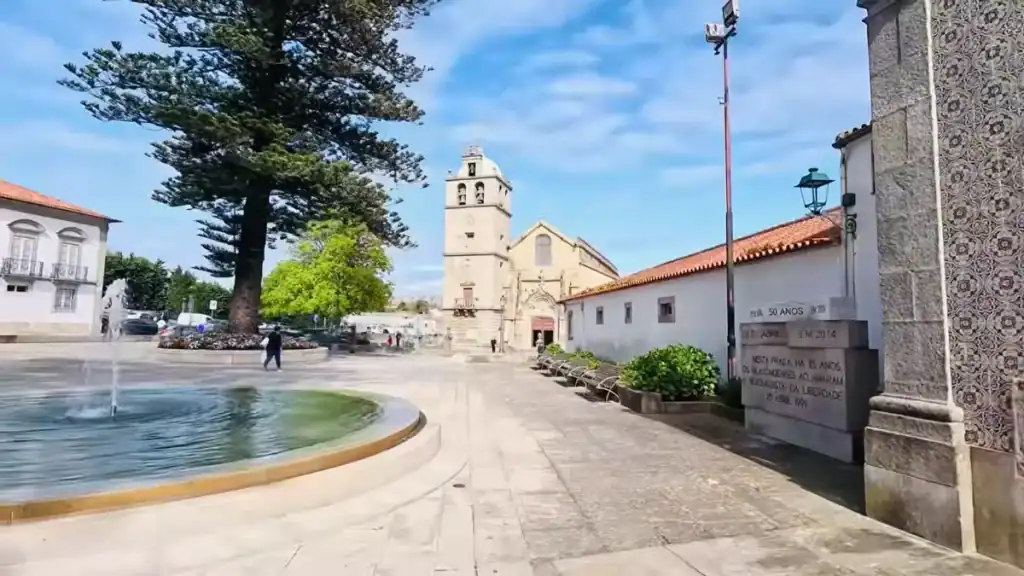 Circular fountain on an open square with Igreja Matriz bell tower beyond