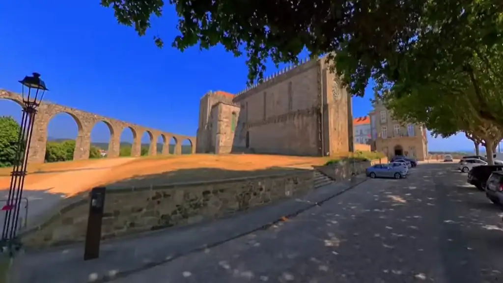Gothic church facade of the Vila do Conde monastery beside the arched aqueduct on a sunny day