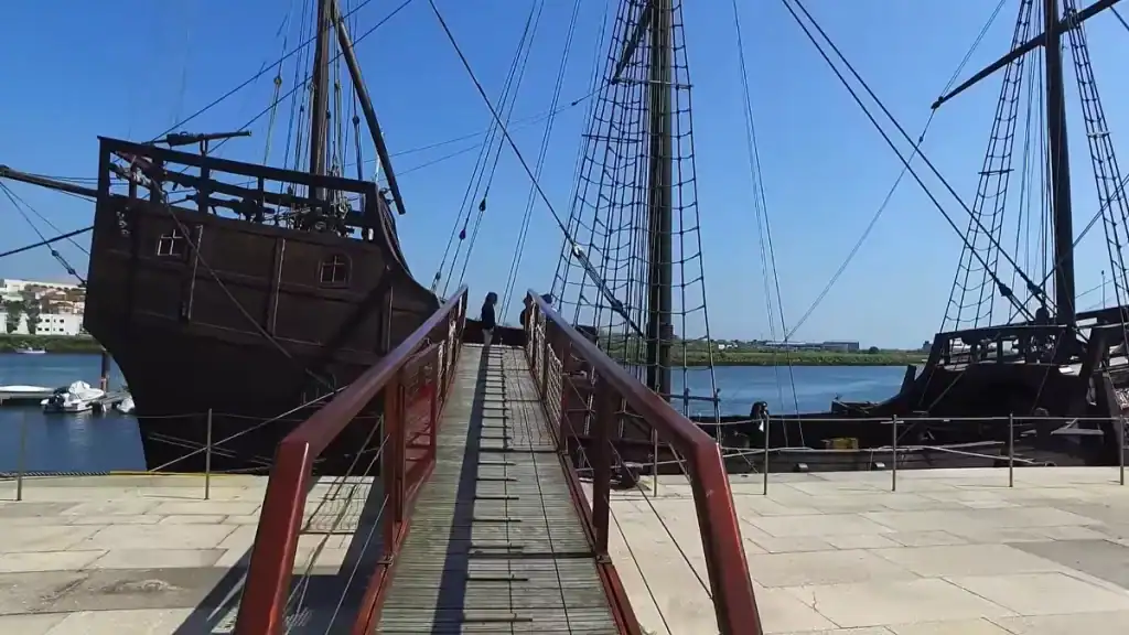 Gangway leading onto a replica Portuguese caravel moored at a riverside dock