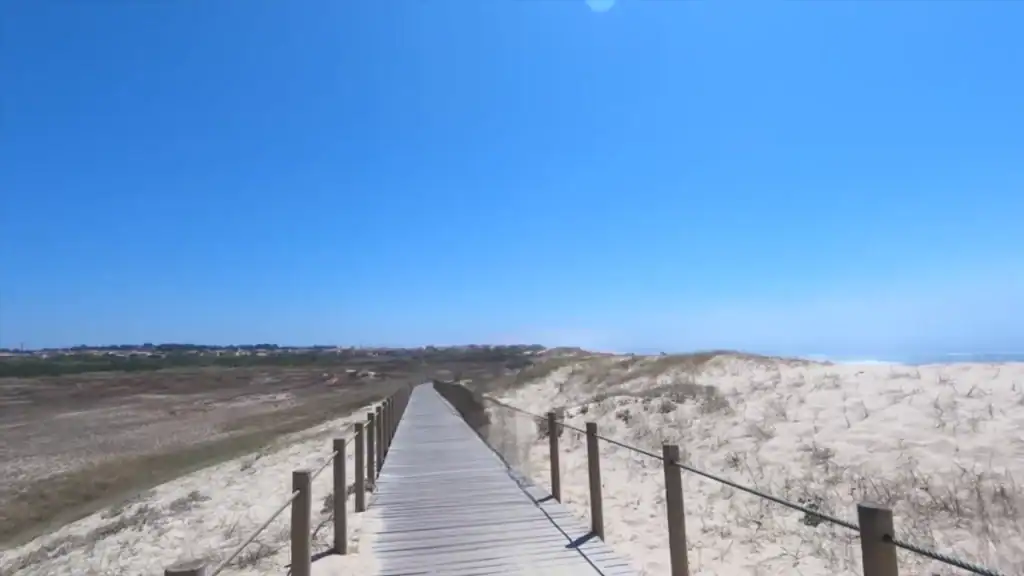 Wooden boardwalk cutting through white sand dunes toward the Atlantic, Vila do Conde worth visiting for its coastline