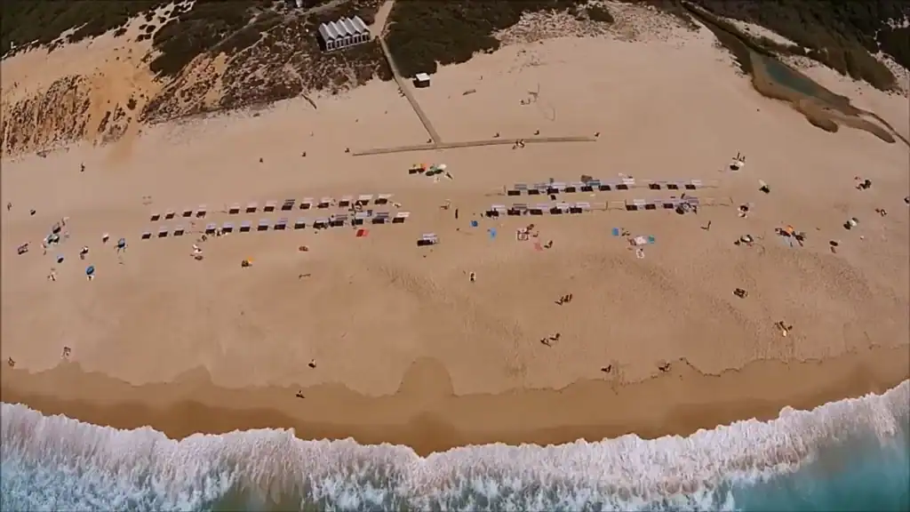 Aerial view of Aberta Nova beach with rows of sun loungers and Atlantic waves