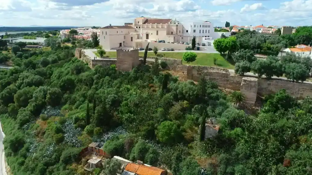 Moorish castle walls and converted pousada building surrounded by dense greenery on a hilltop