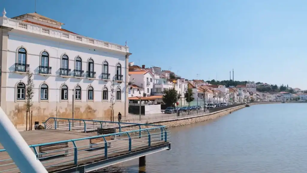 Whitewashed riverfront buildings and wooden jetty along the Sado in Alcácer do Sal on a clear day