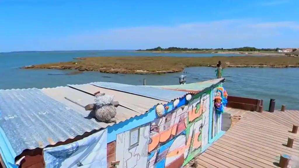 Colourful graffiti-covered fishing hut on a wooden pier overlooking the Sado Estuary