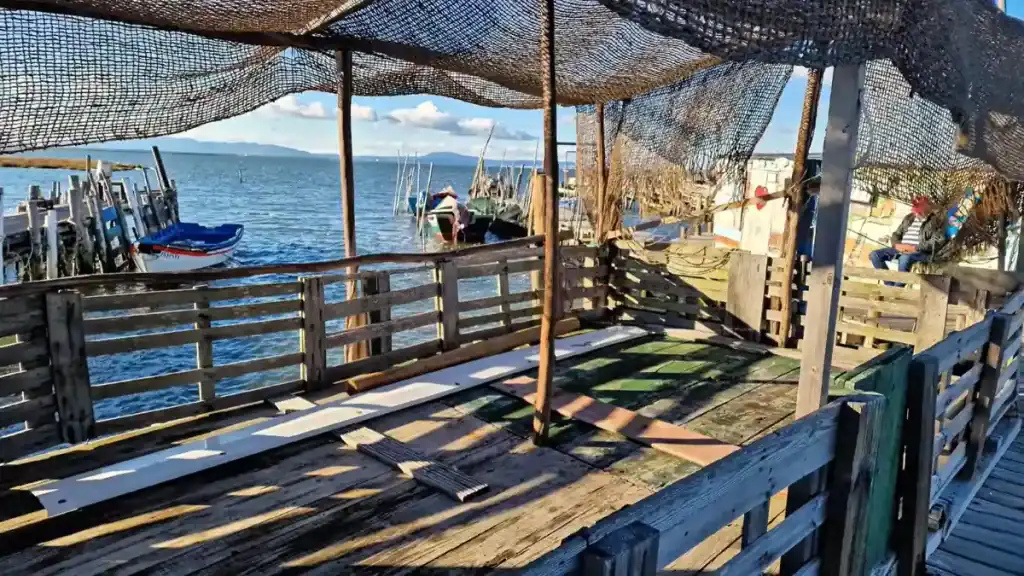 Fishermen resting beneath net canopy on a Carrasqueira pier walkway with boats beyond
