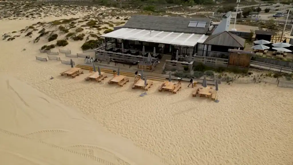 Aerial shot of Sublime beach club Carvalhal with wooden sun tables set out on pale sand