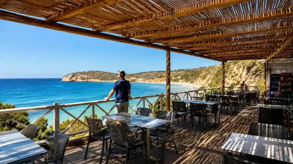 Man on a bamboo-shaded taverna terrace looking out over Istron Bay