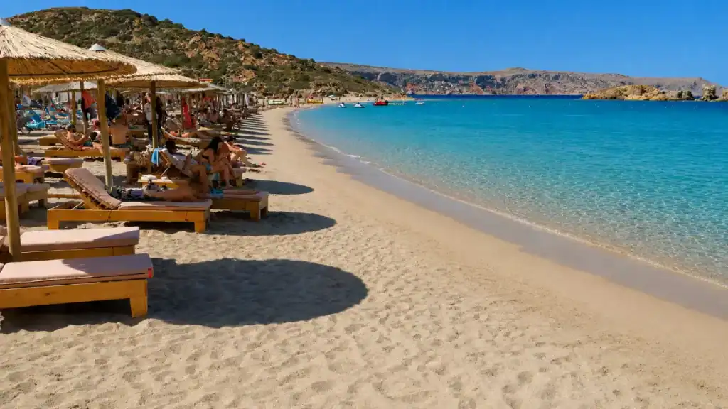 Wooden sunbeds and straw umbrellas curving along Vai Beach, among the best beaches in East Crete