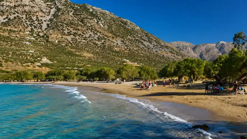 Mountains rising behind the curved sandy bay at Tholos Beach near Kavousi