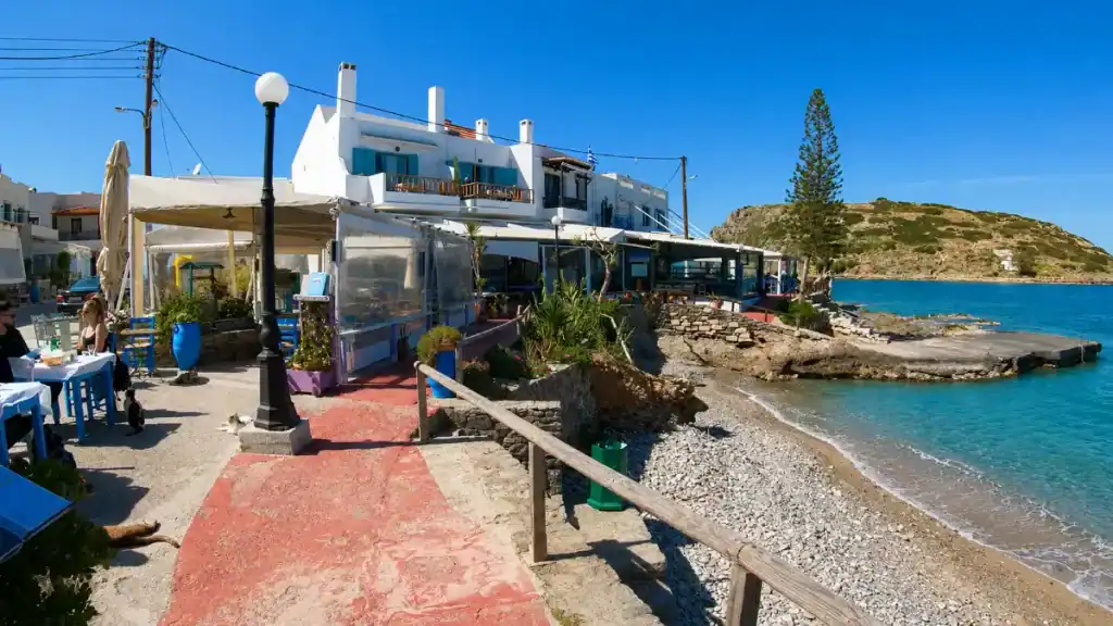 Waterfront tavernas and pebble shoreline facing the small islet at Mochlos village.