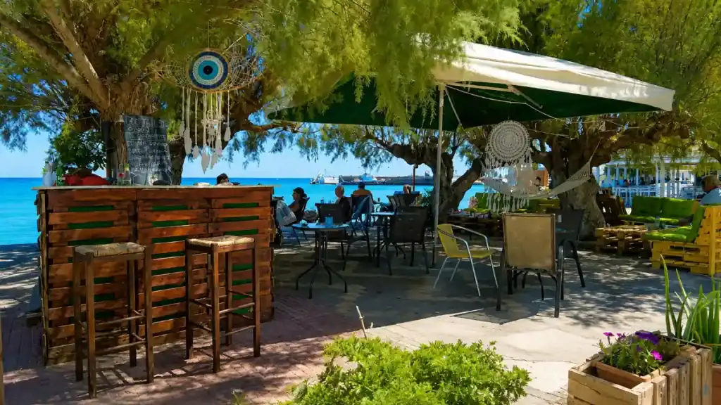 Shaded beach bar with pallet furniture and evil eye charms on Ierapetra seafront