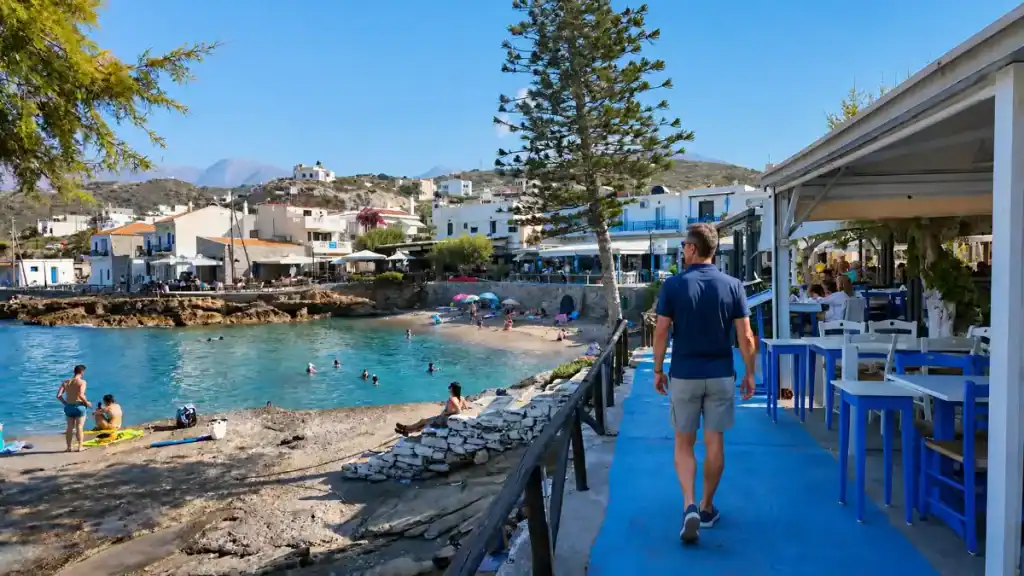 Man walking past blue taverna chairs along the Mochlos seafront promenade
