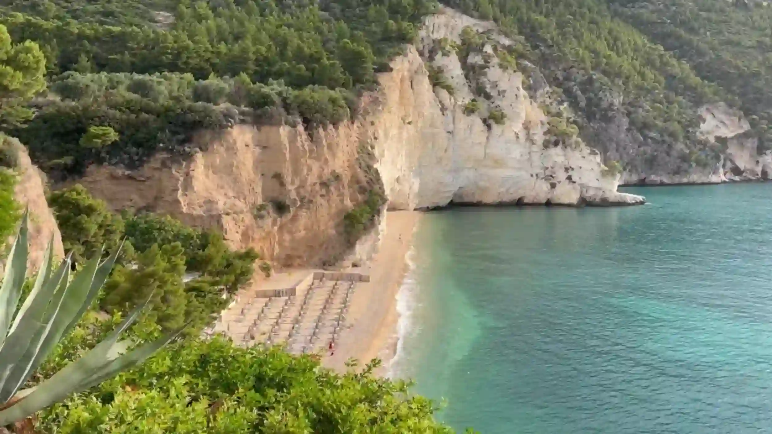 Empty sun loungers line the sandy shore of Baia delle Zagare in October.