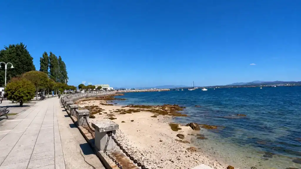 Tree-lined promenade and rocky shoreline along O Grove's waterfront in Baiona and O Grove, Galicia