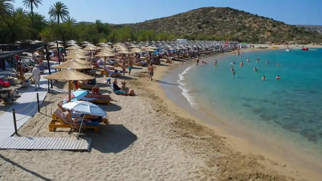 Straw umbrellas and sunbeds line the sandy shore at Vai beach, eastern Crete